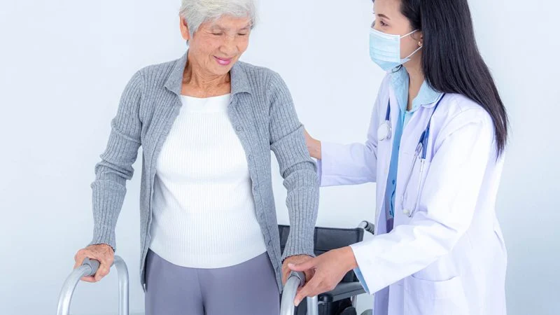 Kalça Kırığı Ameliyatı Sonrası Doktor Eşliğinde Yürüyen Yaşlı Kadın