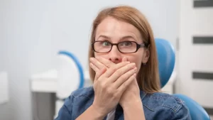 ağız kokusu nedeniyle ağzını kapatan gözlüklü kadın